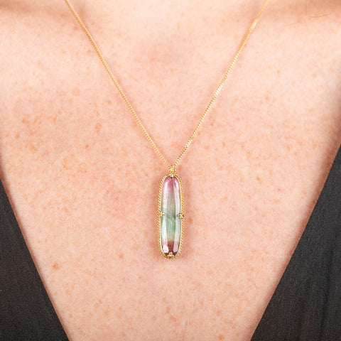 Handmade necklace with a watermelon tourmaline gemstone set in a gold bezel on a person