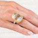 Gold and silver ring with a lodolite quartz stone on a hand against a white background