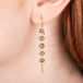 Gold earrings featuring five grey diamonds each, shown worn on a person's ear.
