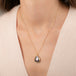 Gold necklace featuring a mabe pearl stone worn on a person's neck.