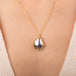 Gold necklace featuring a mabe pearl set in a handcrafted 18k gold bezel, worn on a person's neck.