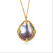Gold necklace featuring a mabe pearl set in a handcrafted 18k gold bezel, against a white backgorund.