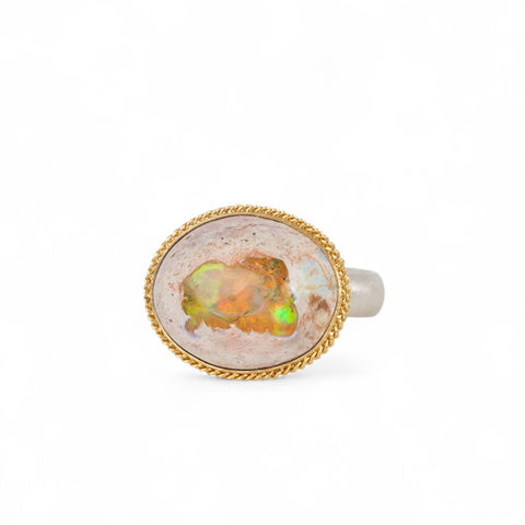 Ring with Mexican opal stone, gold bezel and sterling silver band on a white background
