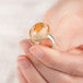 Hand holding a mexican opal ring set with a handcrafted 18k gold bezel and sterling silver band