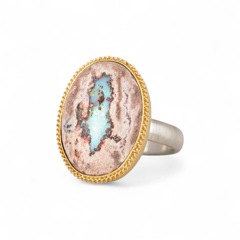 Handcrafted ring with a mexican opal stone, gold setting and sterling silver band on a white background