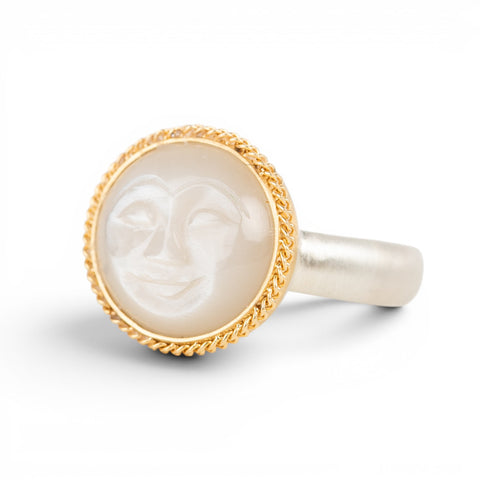 Gold moonstone ring with a moon face design on a white background