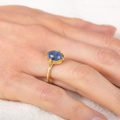 Gold ring with a moonstone on a hand against a white background