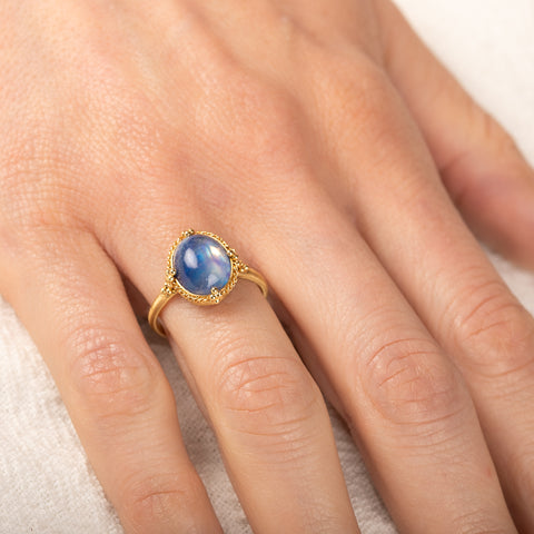 Gold ring with a moonstone on a person's finger