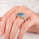 A hand wears a handmade gold and silver ring with a Moonstone gemstone