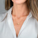 A gold necklace featuring a moonstone gem, worn on a person's neck.