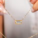 A close up of a gold necklace featuring a moonstone gem held in hand.