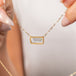 A close up of a gold necklace featuring a moonstone gem held in hand