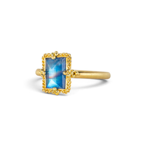 A gold ring featuring a rectangular moonstone set in a 18k gold bezel, against a clean white background.