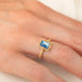 A gold ring featuring a rectangular moonstone set in a 18k gold bezel, worn on a person's finger.