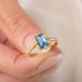 A gold ring featuring a rectangular moonstone set in a 18k gold bezel, held in hand.