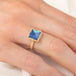 A gold ring featuring a blue moonstone gemstone, worn on a finger.