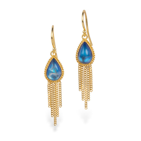 A pair of gold drop earrings featuring teardrop-shaped blue iridescent moonstone gemstones surrounded by a textured gold bezel, with dangling gold chain fringe, shown on a white background.