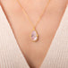 Teardrop-shaped morganite necklace set in an 18k gold bezel and matching chain, worn on a person's neck.