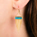 A gold dangle earring featuring a rectangular boulder opal and cascading gold chain fringe, shown worn on a person's ear.