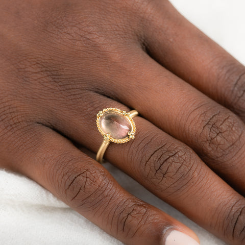 Gold ring with a sunstone on a person's finger