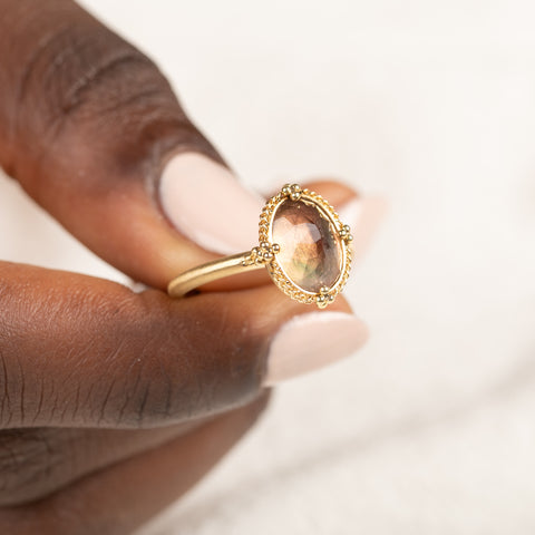 Gold ring with a sunstone held in hand