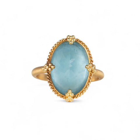 Handcrafted 18k gold ring with a blue aquamarine gemstone on a white background.