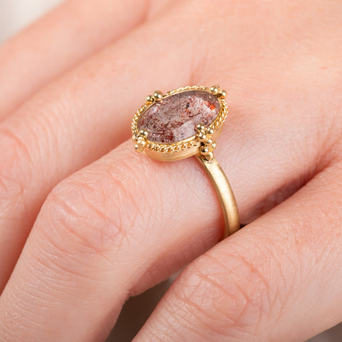 A photo showing the close up details of a handmade 18k yellow gold and Super 7 gemstone ring.