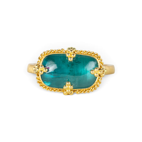 Gold ring featuring a teal pariba kyanite stone set in an 18k gold bezel, shown against a white background.