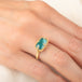 Gold ring featuring a teal pariba kyanite stone set in an 18k gold bezel, worn on a person's finger.