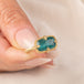 Gold ring featuring a teal pariba kyanite stone set in an 18k gold bezel, held in a hand.