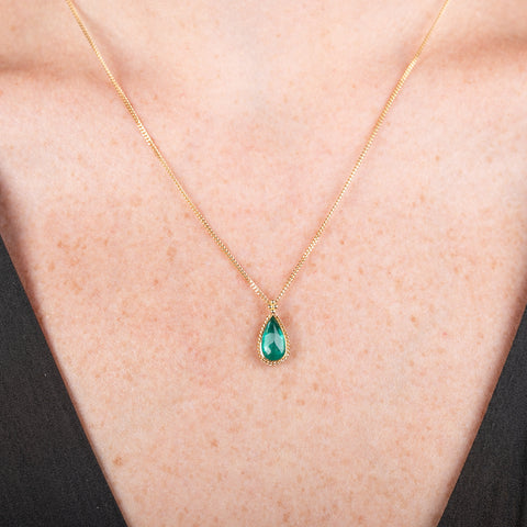 Handcrafted gold necklace with a one-of-a-kind emerald teardrop pendant on a model's neck.
