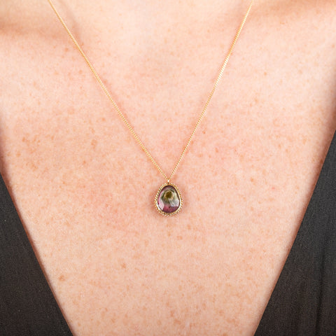 Handmade necklace featuring a watermelon tourmaline gemstone set in a 18k gold bezel on a person