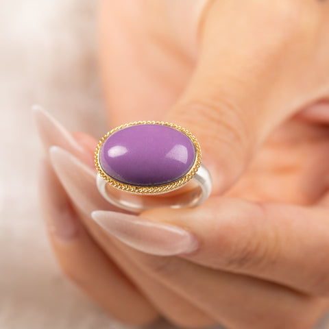 A gold and silver ring featuring a phosphosiderite stone, held in hand.