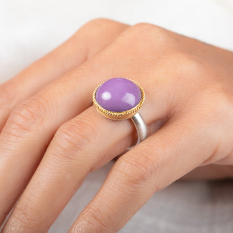 A gold and silver ring featuring a phosphosiderite stone, worn on a person's finger.