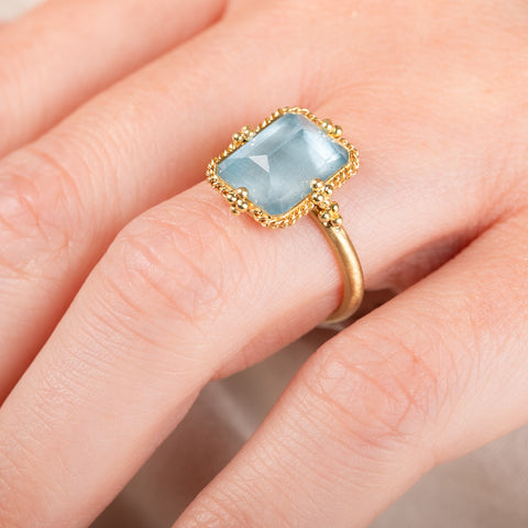 A photo that shows the close up details of a handcrafted 18k yellow gold and aquamarine ring.