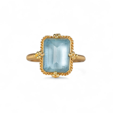 18k gold ring with a rectangular aquamarine gemstone on a white background.