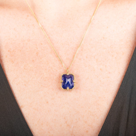 Handmade gold necklace with a blue tanzanite gemstone pendant on a person