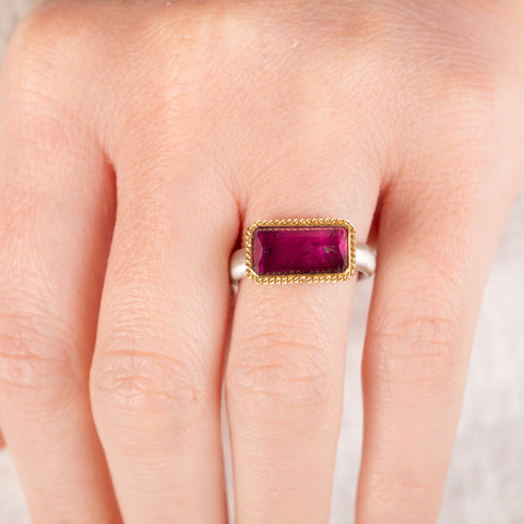 Hand wearing a tourmaline ring with gold bezel and silver band