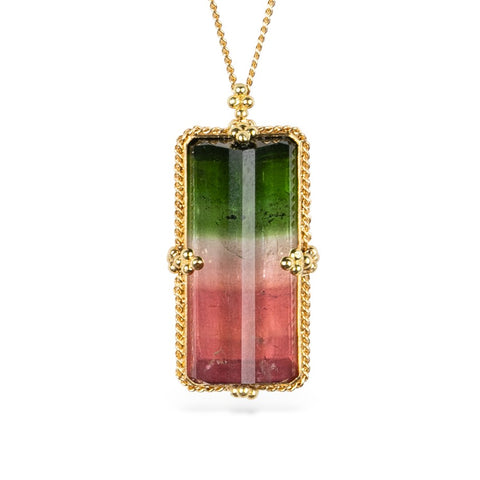 Watermelon tourmaline gemstone necklace with a gold setting against a white background