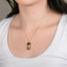 Watermelon tourmaline gemstone necklace with a gold setting worn on a person