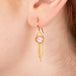 Gold earrings featuring rhodochrosite gemstones and gold chain tassels, shown worn in a person's ear.