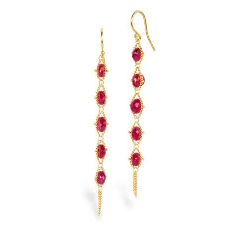 Gold earrings featuring a row of five ruby stones, shown against a white background.