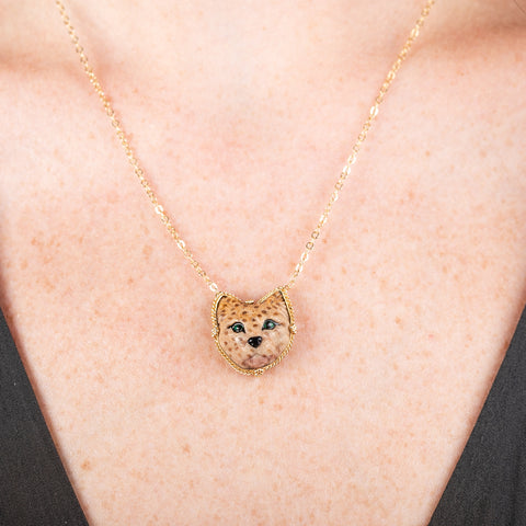 Handmade gold necklace featuring a carved spotted cat made of jasper on a person's neck.