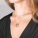 Handmade gold necklace featuring a carved spotted cat made of jasper worn on a person.
