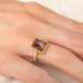 A gold ring featuring an Oregon Sunstone gemstone in a 18k gold bezel setting, worn on a person's finger.