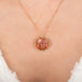 Gold necklace with a circular sunstone pendant featuring a sun face design on a person's neck