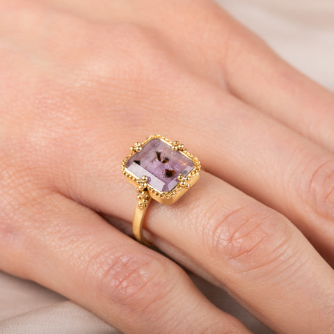 Gold ring with a purple Super 7 gemstone on a hand
