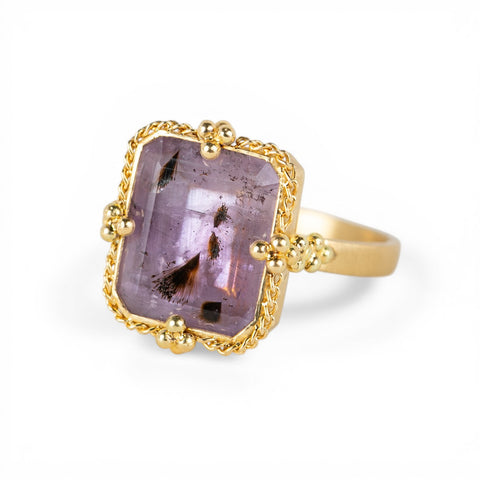 Gold ring with a purple Super 7 gemstone on a white background