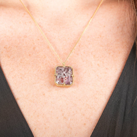 Handmade gold necklace with a Super 7 gemstone on a person