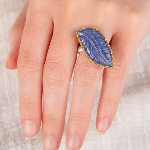 A hand carved tanzanite feather ring with a gold bezel and sterling silver band